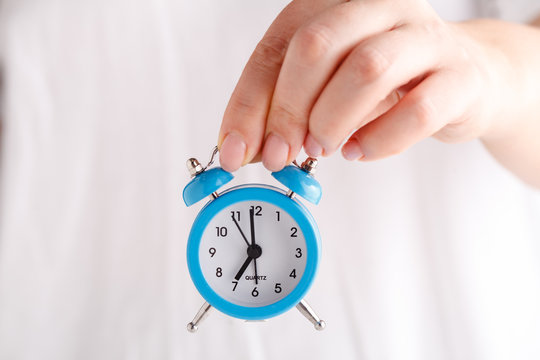 female hands holding alarm clock