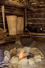 Traditional interior of a European historic residential building with a hearth and cooking pot