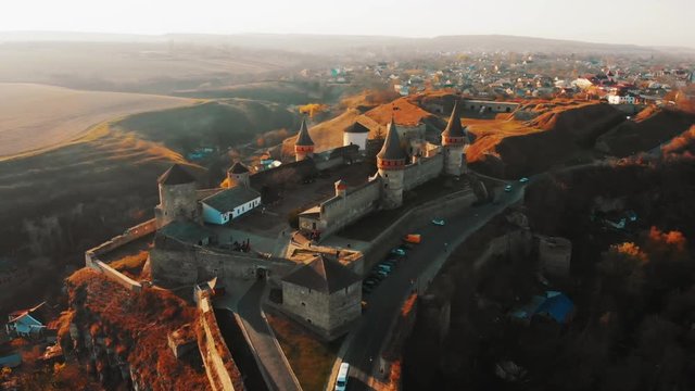 Aerial view of Kamianets-Podilskyi fortress in Ukraine. Castle built in 14th century on Smotrych river. Architecture of Middle Ages in our time. Travel concept. Autumn sunflares light