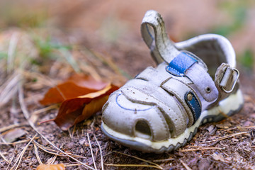 Verbrechen / Entführung? - ein einzelner, kleiner  Kleinkindschuh, der allein im Wald am Boden liegt