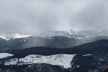 Fototapeta na wymiar Mist rises as dramatic snowstorm moves across mountain valley