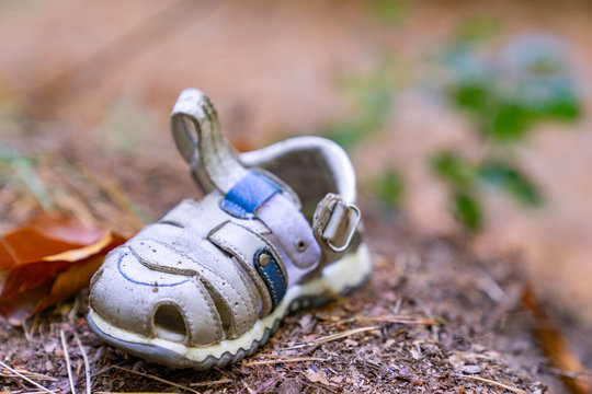 Verbrechen / Entf&uuml;hrung? - ein einzelner, kleiner  Kleinkindschuh, der allein im Wald am Boden liegt