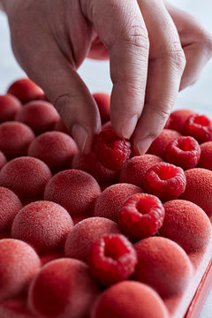 Chef decorating cake with raspberries