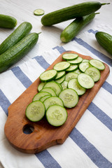 Chopped raw organic green cucumbers on rustic wooden board, low angle view. Close-up.
