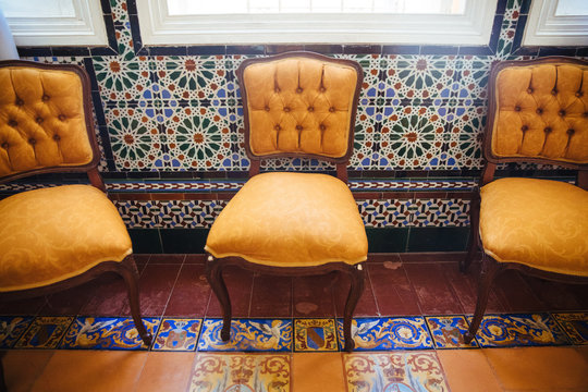 Orange covered cloth chairs in a dining room with colorful Cuban tilework