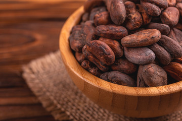 Bowl full of aromatic raw cocoa beans with burlap napkin