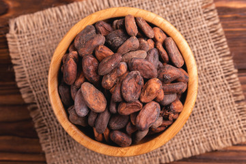 Bowl full of aromatic raw cocoa beans with burlap napkin
