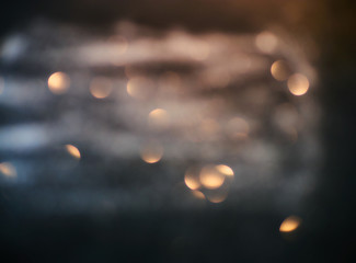 Blurred background lights. Abstract defocused gold, white, red and yellow glitters texture on black background. Shining glowing snow effects