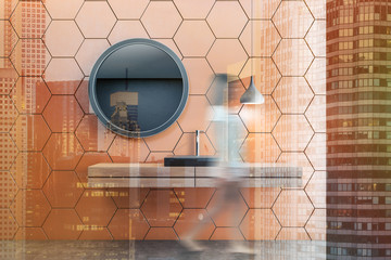 Orange honeycomb bathroom, black sink, woman