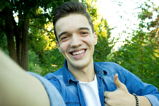 Young boy smiling at the park is taking selfie.