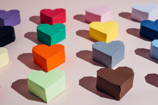 Various color paper hearts on a pink background
