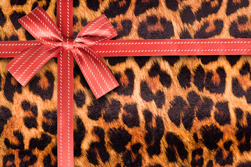 Red gift ribbon on a leopard pattern texture. Gift box wrapping concept.