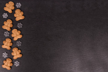 Gingerbread cookies and snowflakes in decoration on slate in background, directly above.