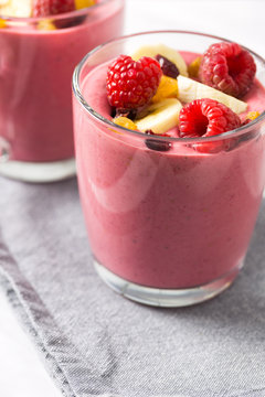 Glass of smoothie with banana and raspberries