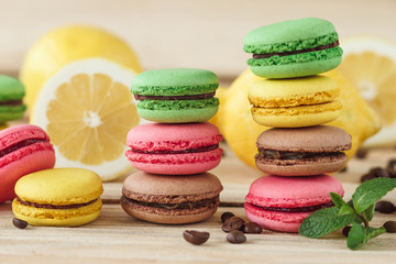 Green, pink, yellow and brown french macarons with lemon and coffee beans