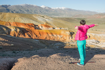 Naklejka premium Happy woman standing on rock. Mars mountains, the name of colored mountain protrusions in the mountains of Kyzyl-Chin. Altai, Russia. A delightful landscape of unreal beauty.