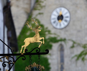 gold deer sign in Salzburg street with blur clock in background