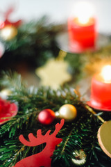 Homemade traditional German Advent wreath, a round circle with fir branches, red and golden Christmas ornaments and cut out paper elks, DIY crafting project idea at holiday season with kids