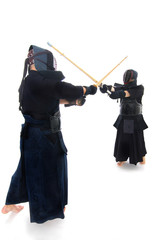 Kendo fighters training with bamboo swords in studio on white background.