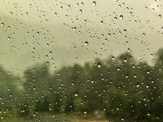 Raindrops on the glass window with blurry garden background, GA USA.