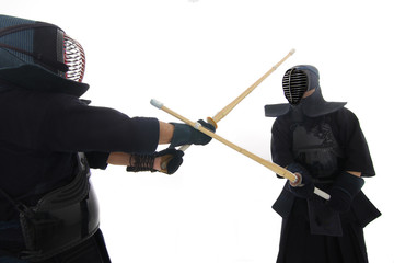 Kendo fighters training with bamboo swords in studio on white background.