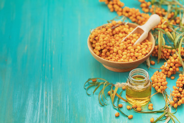Natural, organic sea-buckthorn berry in wooden dish and sea buckthorn oil in glass vintage bottle