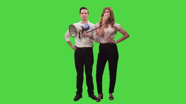 Businesswoman talking through a megaphone while a businessman is holding the speaker and nods in a medium frontal shot over a green screen,