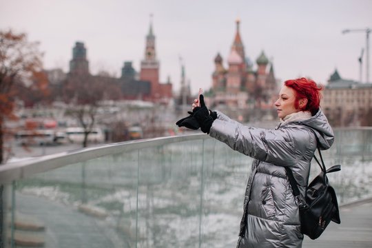 Girl walking by the Flying bridge over Moscow river and taking pictures with her phone
