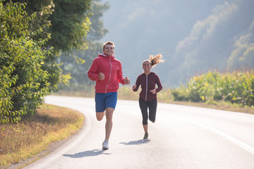 young couple jogging along a country road