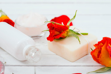 beauty product samples with roses on white wooden, soft light