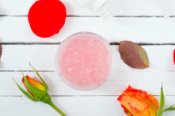 beauty product samples with roses on white wooden, soft light