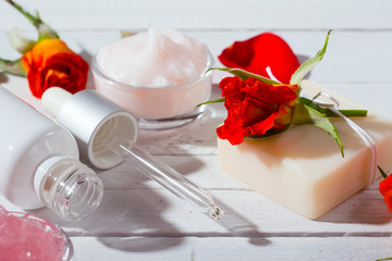 beauty product samples and roses with shade on white wooden table