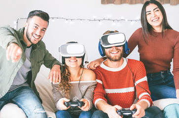 Happy millennials friends playing video games with virtual reality headset - Young people having fun with new vr online trend technology - Gaming, tech and youth concept