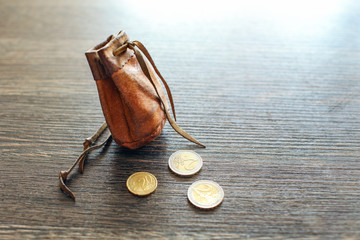 Vintage leather pouch on wooden desk, with euro coins next to it