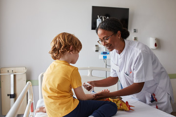 Doctor female giving attention and care to child in a hospital room