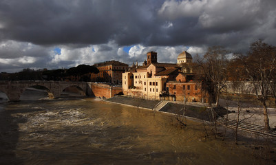 Naklejka premium Winter in Rome. River is swollen along Tiber Island embankments under stormy clouds
