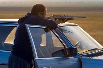The guy shoots cartridges with a gun in nature, The hunter shoots at the target at sunset	