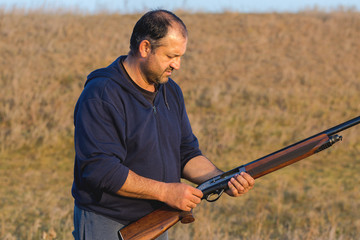 The guy shoots cartridges with a gun in nature, The hunter shoots at the target at sunset	