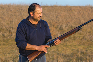 The guy shoots cartridges with a gun in nature, The hunter shoots at the target at sunset	