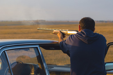 The guy shoots cartridges with a gun in nature, The hunter shoots at the target at sunset	