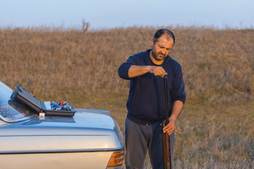 The guy shoots cartridges with a gun in nature, The hunter shoots at the target at sunset	