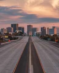 Fototapeta na wymiar Empty San Diego Freeway with Sunset Sky - Vertical view of San Diego, California, USA Skyline with empty freeway in foreground. The 5 freeway travels most of the coast of the western united states