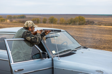 Hunter with a hat and a gun in search of prey in the steppe	