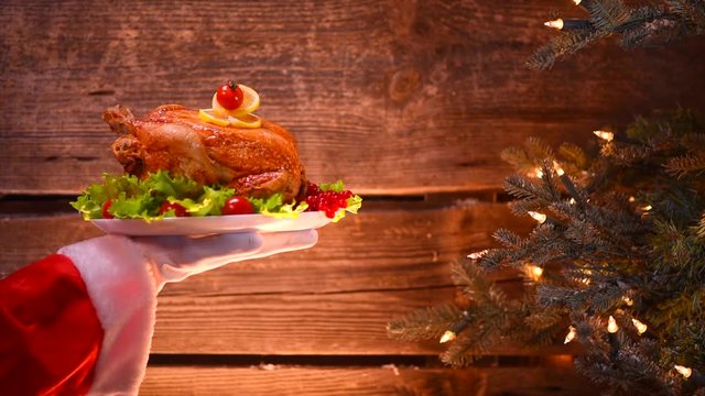 Christmas scene. Holiday dinner. Santa's hand holding roasted chicken. 3840X2160 4K UHD video footage