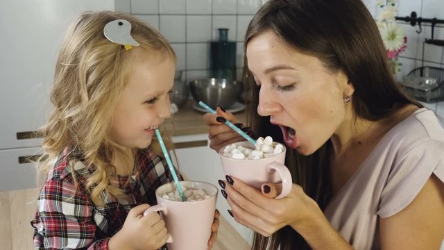 Mother and daughter drink cocoa with marshmallow