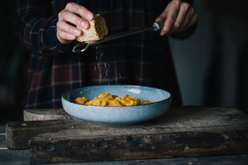 Woman grating cheese on prepared dish