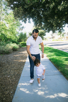 Young dad connecting with child on suburban sidewalk