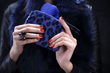 Elegancki modny manicure. Elegancka kobieta w niebieskim futrze trzyma w dłoni torebkę.
