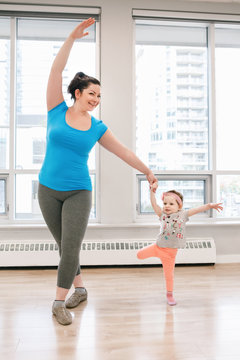 Young woman with child doing workout dancing in gym class to loose baby weight. Child-friendly fitness for mothers with kids toddlers. Lifestyle concept of parent activity.