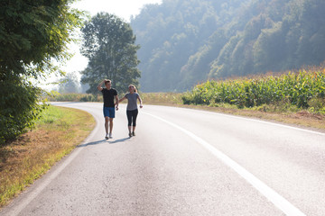 young couple jogging along a country road